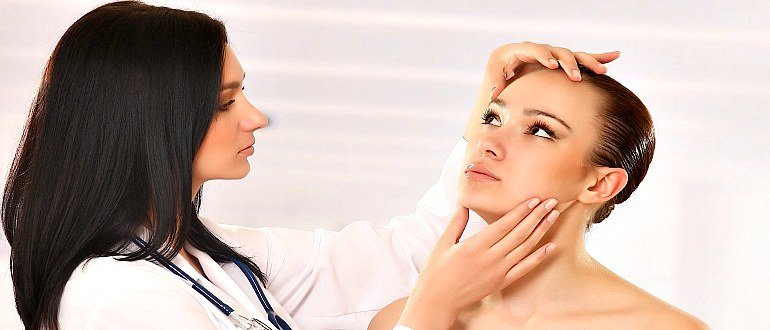 Косметолог осматривает лицо пациентки 