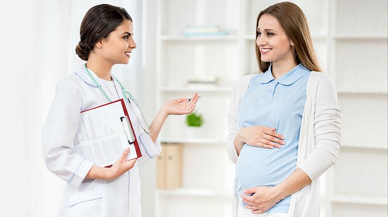 Беременную счастливую девушку консультирует доктор