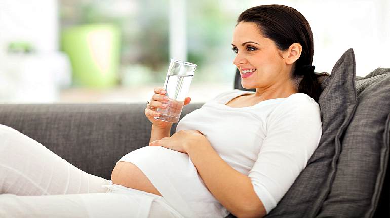 Беременная женщина со стаканом с водой