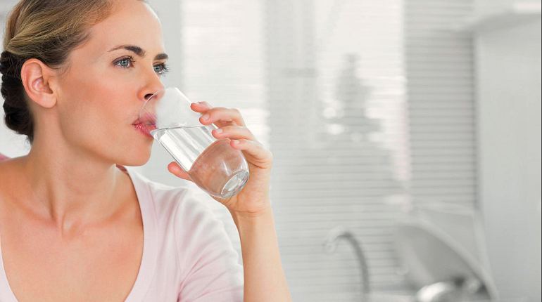 Женщина пьет чистую воду