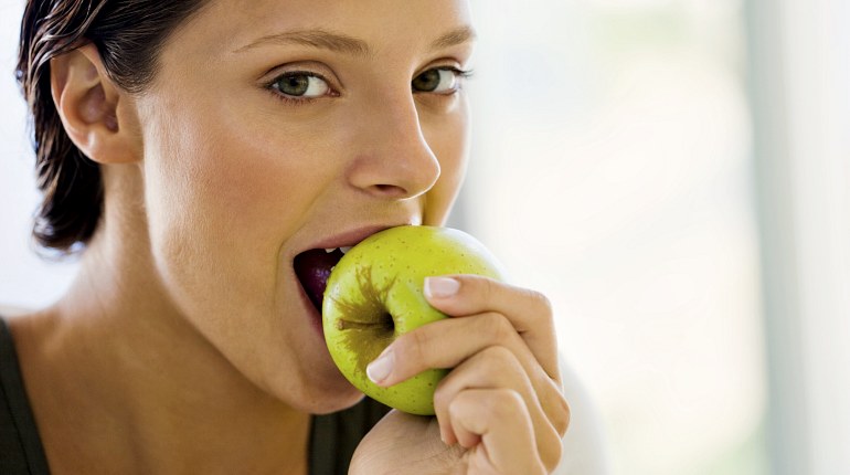 Женщина ест яблоко